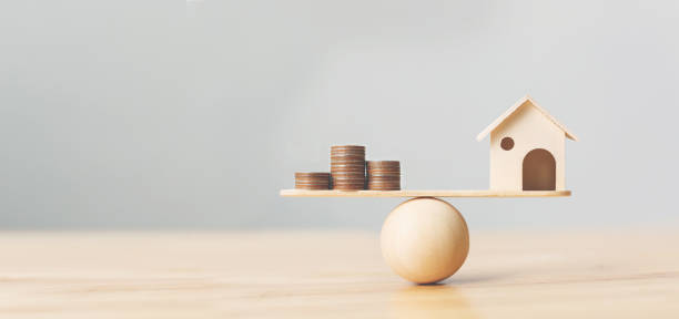 Wooden home and money coins stack on wood scale. Property investment and house mortgage financial real estate concept Wooden home and money coins stack on wood scale. Property investment and house mortgage financial real estate concept scale business stock pictures, royalty-free photos & images