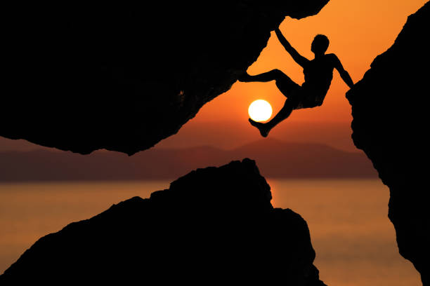 istock Silhouette man Climbing between rocks with red sky sunset background 1136496977