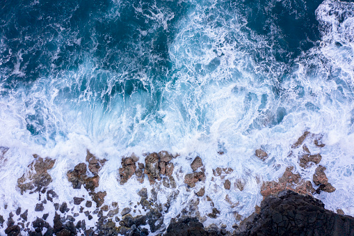 Aerial view of ocean waves breaking on rocky beach