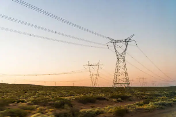 Photo of Electricity power tower line pylons at the sunrise. Concept of energy, connectivity, industry, infrastructure, and technology