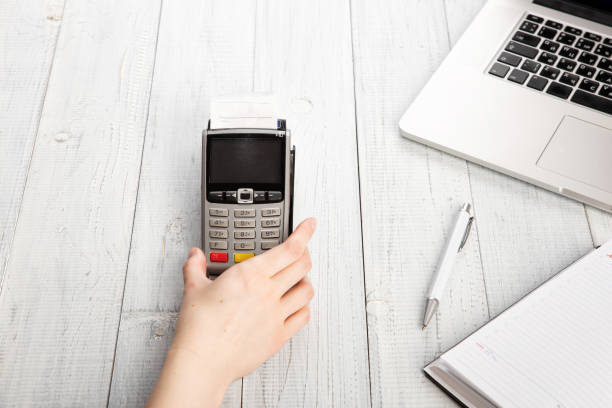 istock Woman's hand holds Payment terminal on white wooden background. 1136505736