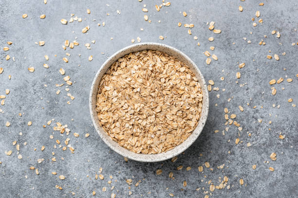 rolled oats or oat flakes in bowl - oatmeal rolled oats oat raw imagens e fotografias de stock