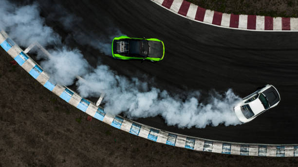 dois carros que deriva a batalha na trilha de raça com fumo, batalha da derivação do carro da vista aérea dois. - motor racing track - fotografias e filmes do acervo