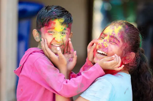 Photo of Cute adorable siblings playing with colours during holi festival of colors Indian asian caucasian creative portrait