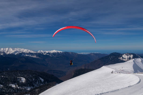 los snowboarders, esquiadores en acción en las montañas. paraglider con instructor. - paragliding sport austria parachuting fotografías e imágenes de stock