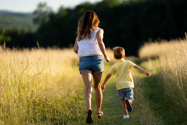 istock rear view mother and son running over summer meadow 1136516573