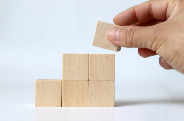 istock A hand piling up a wooden block with a staircase shape. 1136518637