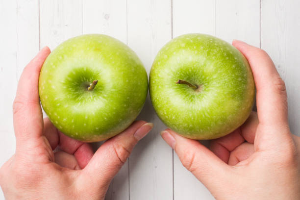 istock Diet concept. Two green Apple hold in palms on the white table. 1136519610