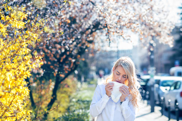 Woman sneezing in the blossoming garden Woman sneezing into a tissue hayfever stock pictures, royalty-free photos & images