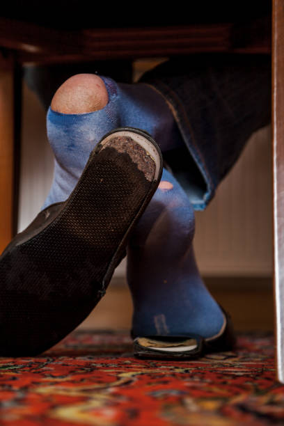istock Man sits on chair on his socks can see holes 1136523088