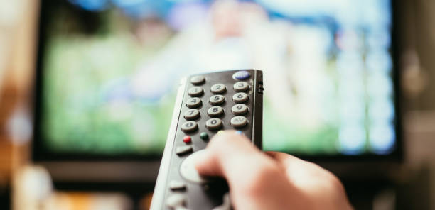 istock Male hand is holding TV remote control, smart TV. 1136523423