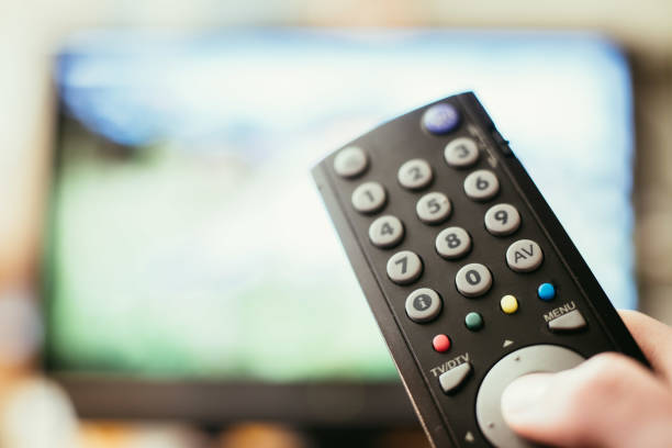 istock Male hand is holding TV remote control, smart TV. 1136523484