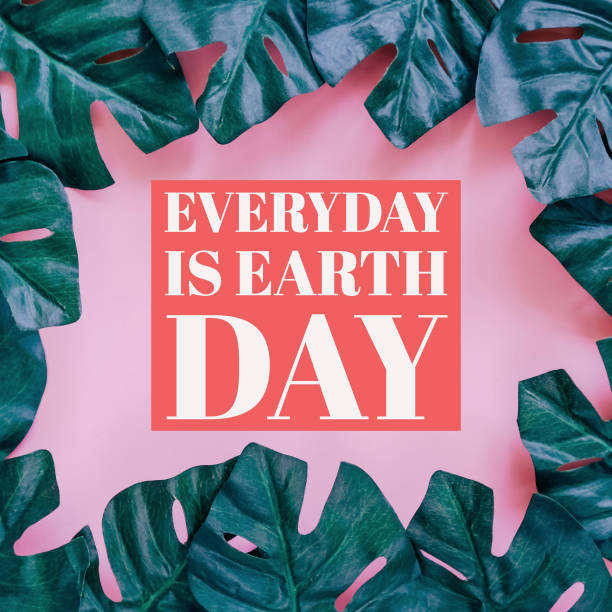 Cornice di foglie di palma verde su sfondo rosa con citazione ispirazionale sul concetto di Giornata della Terra - foto stock