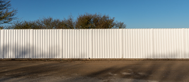 A long white metal fence used as a screen around a building site