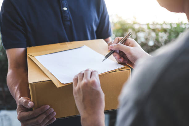 istock High Angle View Of Customer Signing To Receive Package 1136532788