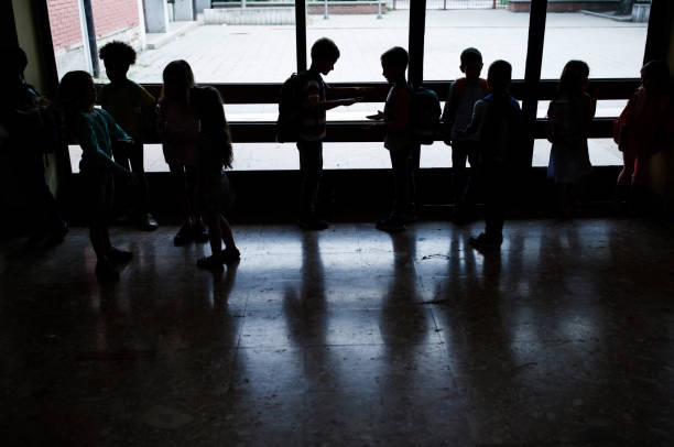 Silhouettes of large group of elementary students in a hallway.