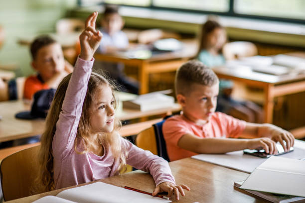 istock Schoolgirl raising her hand on a class at elementary school. 1136539720