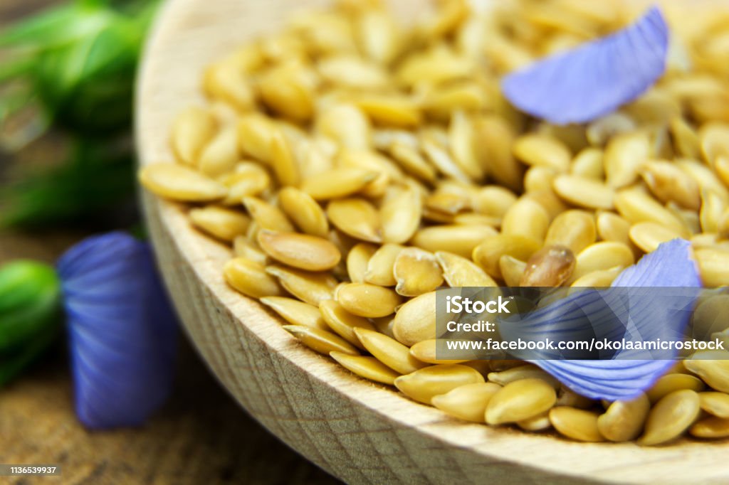 Golden flax seeds with blue flower petals closeup Acid Stock Photo