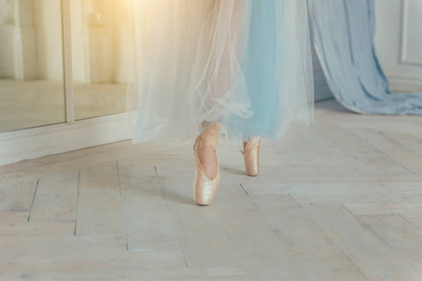 istock Ballerina hands puts pointe shoes on leg in dance class 1136540955