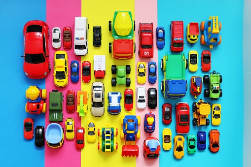Many colored toy cars on multicolored background, top view