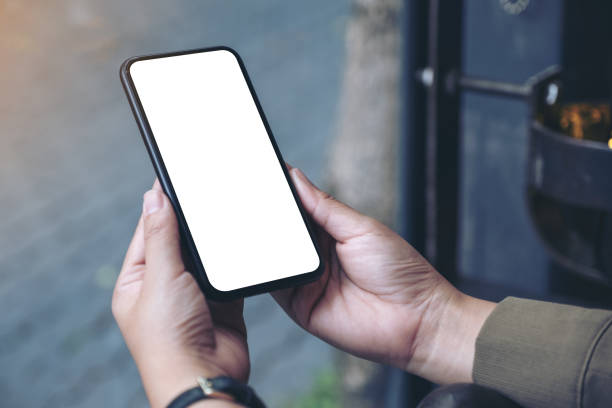 istock Mockup image of hands holding black mobile phone with blank white desktop screen 1136543563