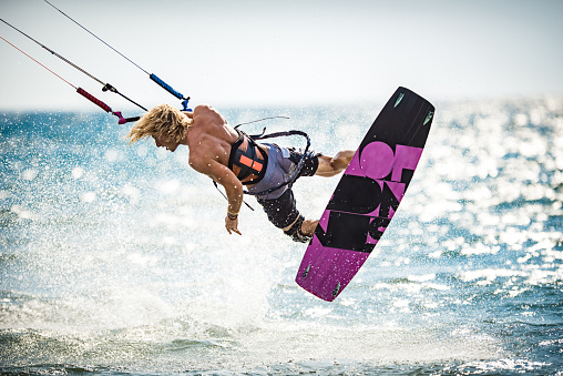 Athletic man having fun while kitesurfing on the sea.