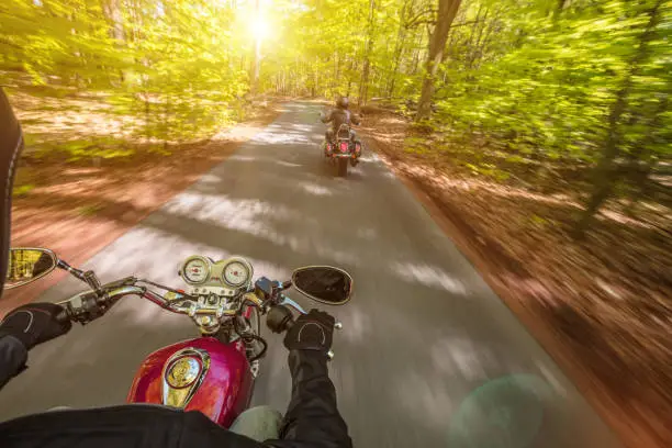 Photo of Motorcycle driver riding in spring forest.