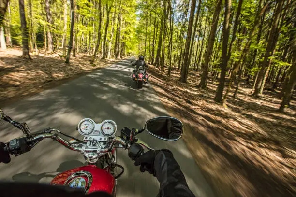 Photo of Motorcycle driver riding in spring forest.