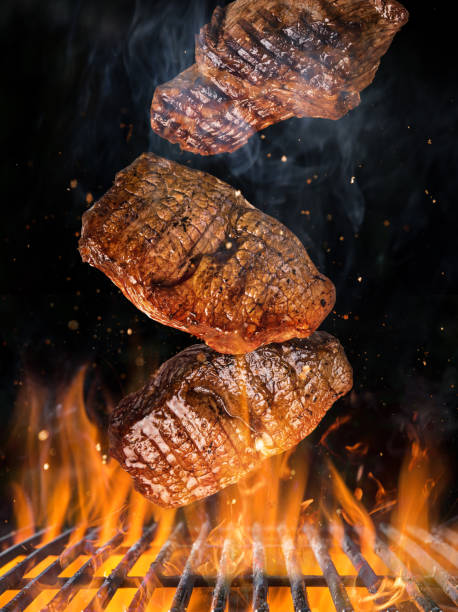 istock Tasty beef steaks flying above cast iron grate with fire flames. 1136546157