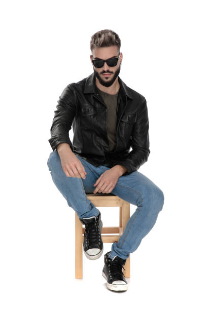istock man in black jacket and blue jeans with arm on knee 1136546255