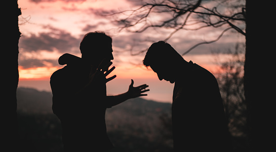 Silhouette of a quarrel between two friends at sunset