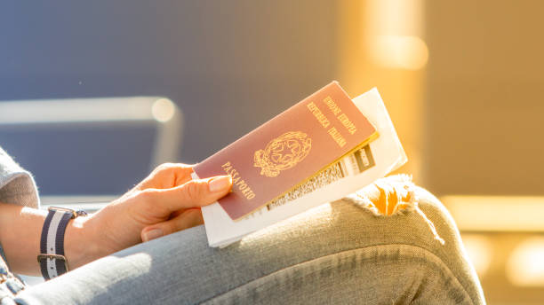 Italian passport and boarding pass in the hands of woman awaiting departure flight in waiting hall - concept of independence and easy traveling in Europe stock photo