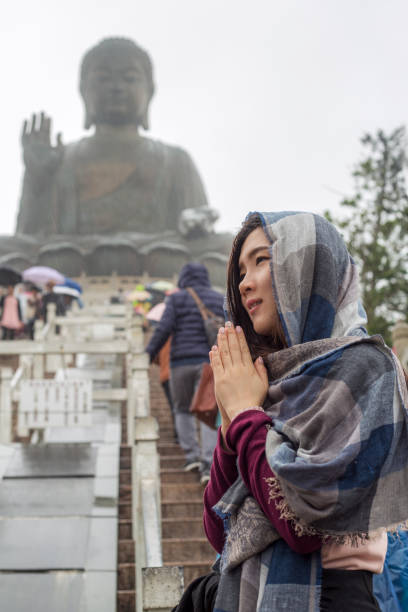 Asian tourist visiting Tian Tan Buddha in Ngong PingLantau Island, Hong Kong, worshipping in rainny day. The Big Buddha, is a large bronze statue of Buddha Shakyamuni, one of the most visited travel destination in HK Asian tourist visiting Tian Tan Buddha in Ngong PingLantau Island, Hong Kong, worshipping in rainny day. The Big Buddha, is a large bronze statue of Buddha Shakyamuni, one of the most visited travel destination in HK tian tan buddha stock pictures, royalty-free photos & images