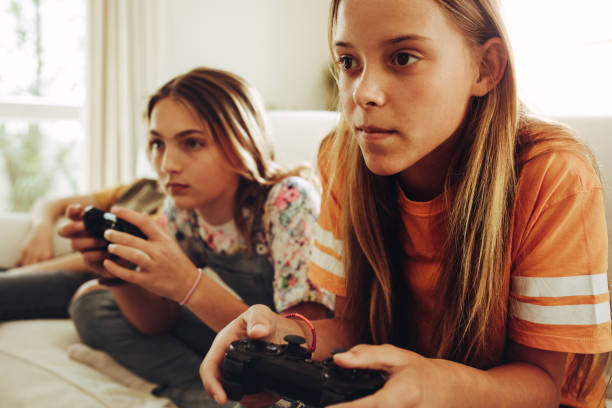 девушки, играющие в видеоигры дома - video game friendship teenager togetherness стоковые фото и изображения