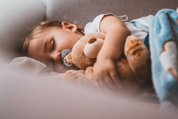 Baby boy sleeping with teddy bear and pacifier Baby sleeping on sofa. Peaceful baby lying on a bed while sleeping in a bright room with his teddy bear. Photo of Child boy sleeping with teddy bear on the bed in his bedroom, New family and baby healthy concept. Sweet Caucasian  one year old child sleeping with teddy bear during the day. baby sleeping bedding bed stock pictures, royalty-free photos & images