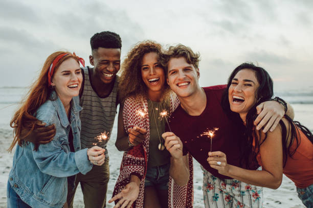 istock Multiracial friends enjoying at beach with sparklers 1136551399