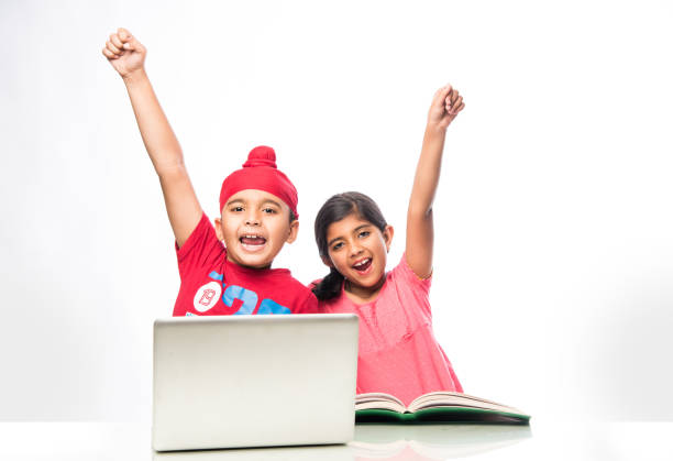 indische sikh/punjabi junge und mädchen studieren mit büchern und laptop-computer am studientisch - junior school stock-fotos und bilder