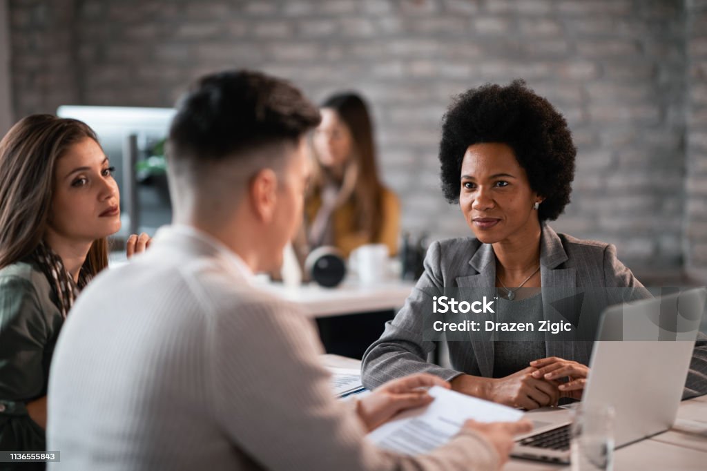 Sorridente agente assicurativo nero che ha un incontro con una coppia in ufficio. - Foto stock royalty-free di Attività bancaria