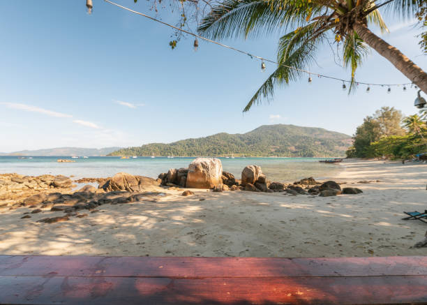 istock Wooden tabletop on coconut tree with rocks on the beach 1136558204