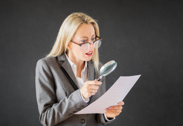 istock Woman reading business contract with magnifying glass 1136558673