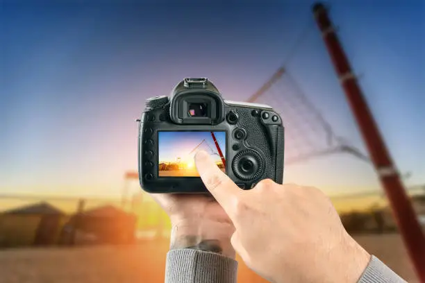 Photo of Digital single-lens reflex camera in hands. Man photographer makes photos. Male hands hold the camera close-up