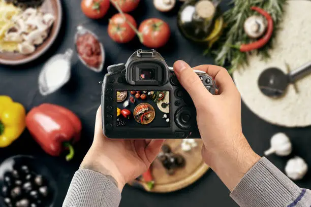 Photo of Digital single-lens reflex camera in hands. Man photographer makes photos. Male hands hold the camera close-up