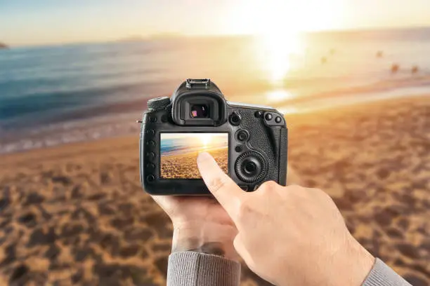 Photo of Digital single-lens reflex camera in hands. Man photographer makes photos. Male hands hold the camera close-up