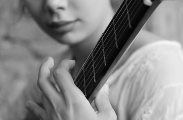 Black and white close-up of ukulele, focus on sound hole top right, strings crossing, shadows below strings, subtle curve left, minimal composition, artistic musical instrument macro, cozy monochrome tone.