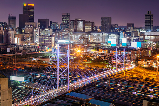 Johannesburg cityscape with Nelson Mandela bridge going over the railway seen close up.\nJohannesburg, also known as Jozi, Jo'burg or eGoli, \