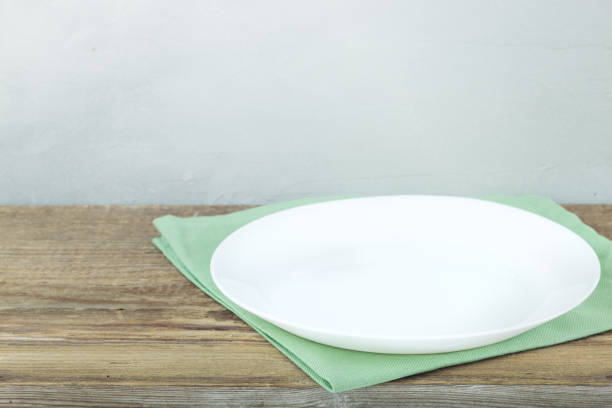 istock Empty plate on tablecloth or napkin on wooden table over cement background 1136563912