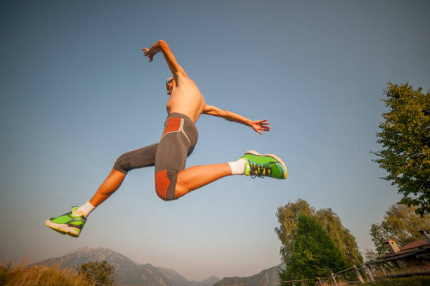 a young man in sportswear jumping in front of the orange wall