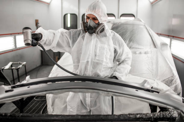 istock Painting technician drying out a freshly painted car bumper using a pneumatic air dryer in a painting booth 1136566712
