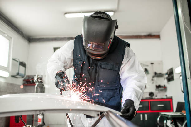 Body repair technician using a MIG welder to repair a damaged car part in a body shop Welding a damaged car part with a MIG welder in a repair workshop. door panel stock pictures, royalty-free photos & images