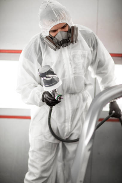 istock Car painter in white overalls spraying a car body with paint 1136568685